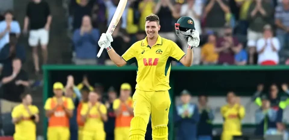 Cricketer celebrating century with raised bat and helmet