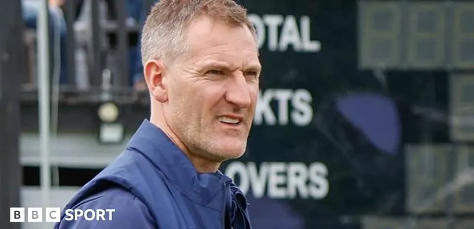 Cricket coach observing match near scoreboard