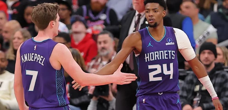 Two Hornets players exchanging a handshake on court