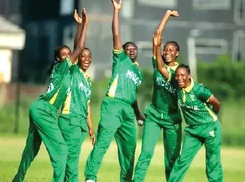 Five female cricketers celebrating on the field