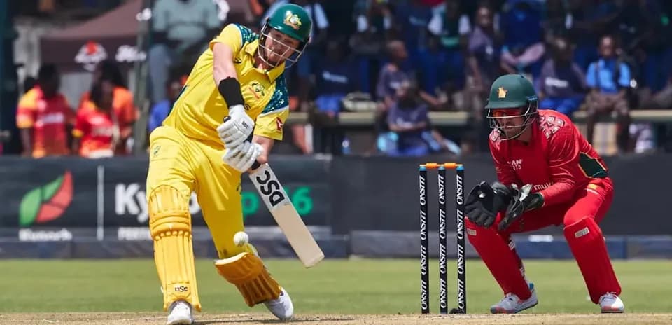 Batsman hitting ball while wicketkeeper prepares to catch