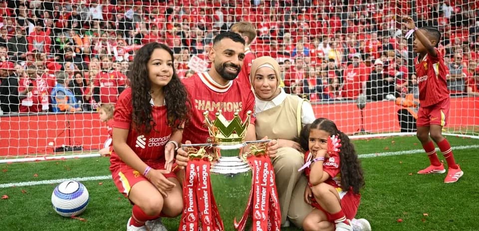 Player holding trophy with family on the field