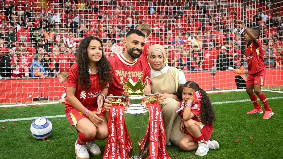 Player holding trophy with family on the field