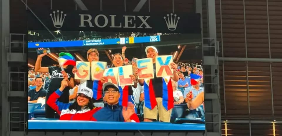 Fans holding signs spelling 'GO ALEX' at match