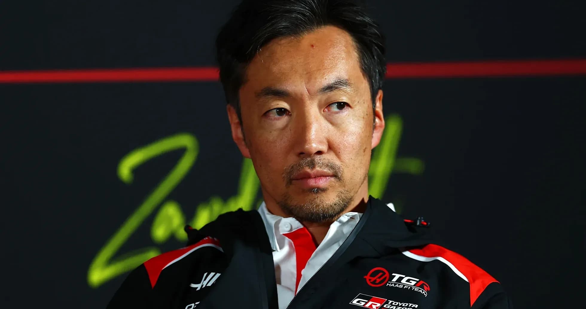 Team member during press conference with serious expression