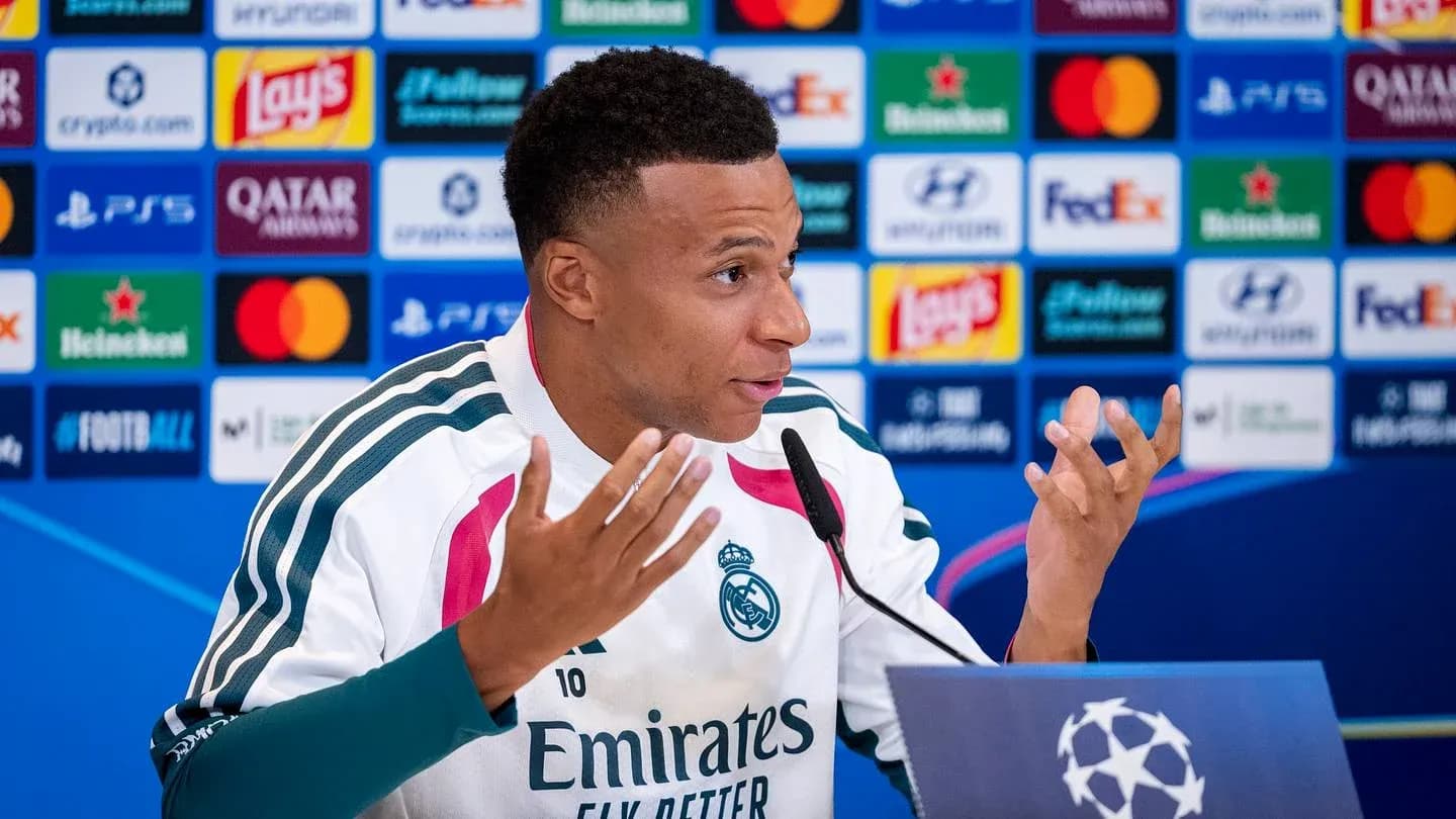 Player speaking at press conference with team logo backdrop