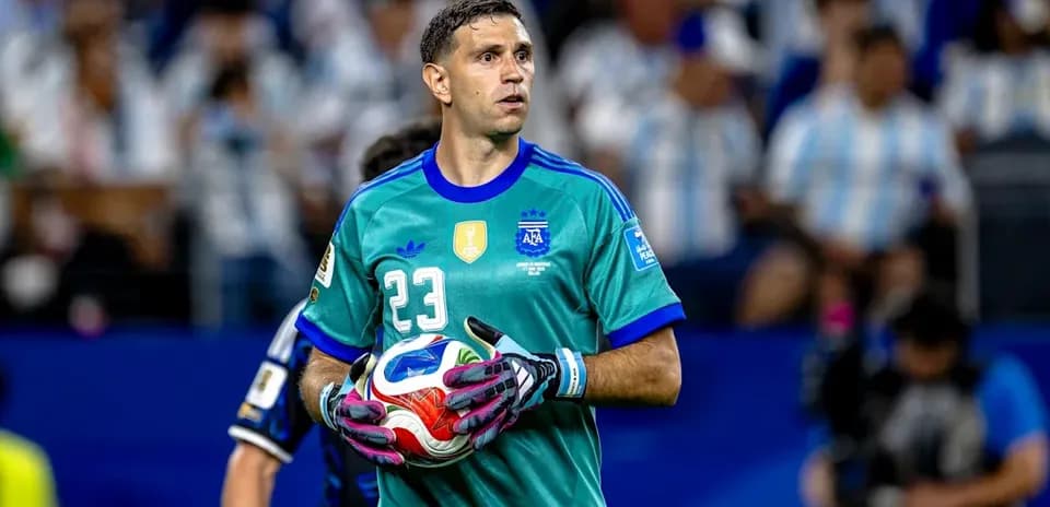 Goalkeeper in turquoise jersey holding a soccer ball