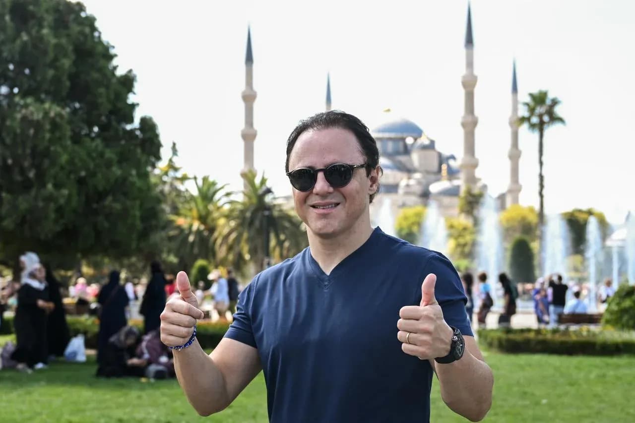 Man giving thumbs up with mosque in background
