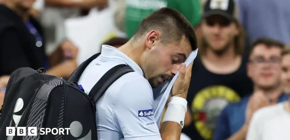 Tennis player wiping face with towel during match
