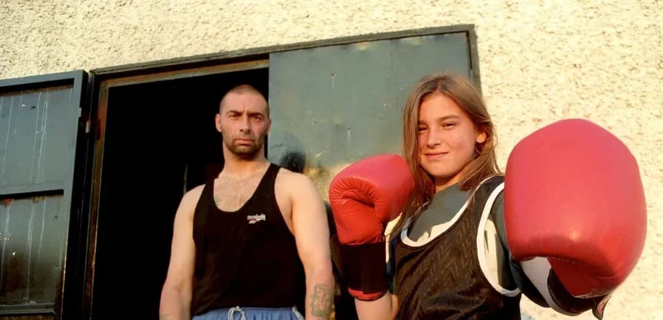 Young female boxer posing with gloves and coach