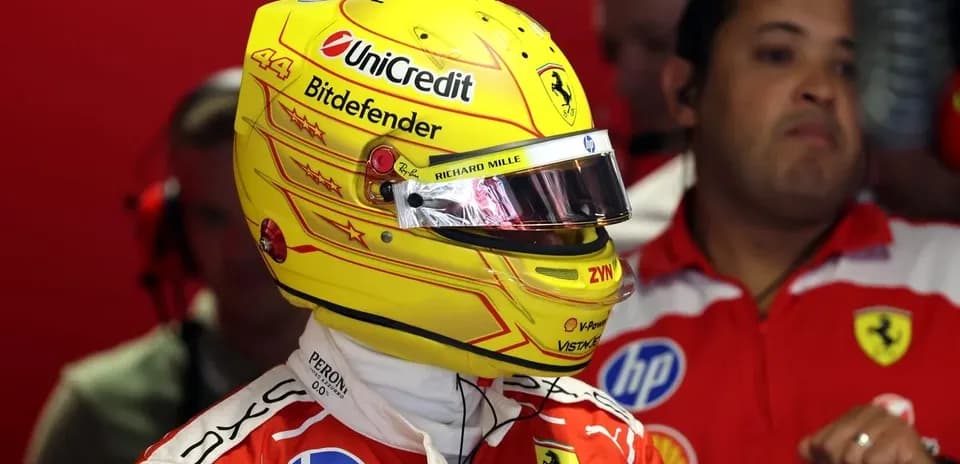 Driver in Ferrari suit and helmet in garage