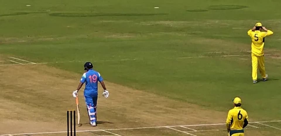 Batsman in blue uniform walking towards the wicket