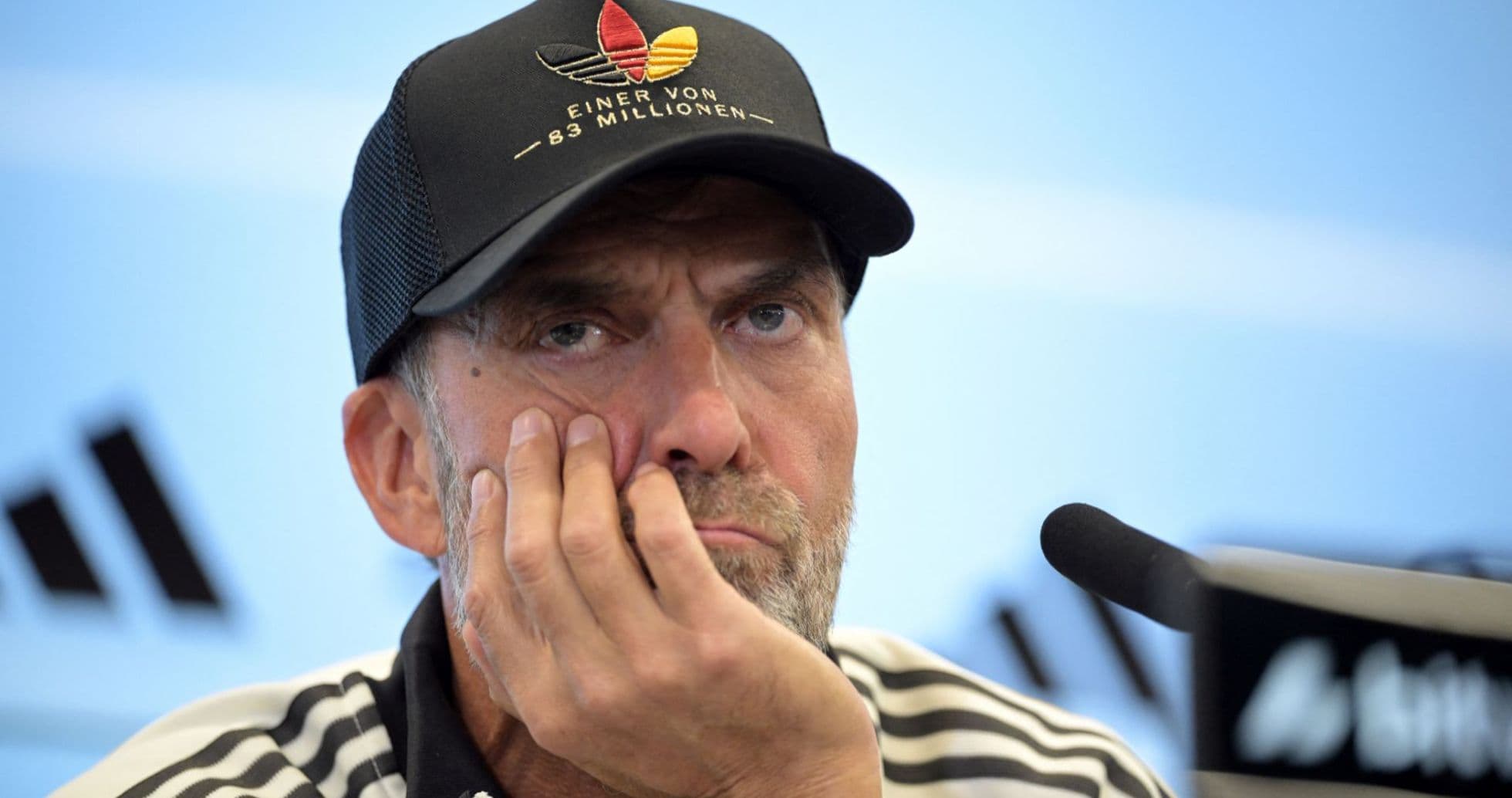 Coach at press conference resting chin on hand