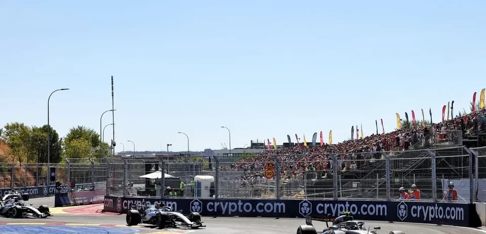 Two Formula 1 cars racing on track with crowd