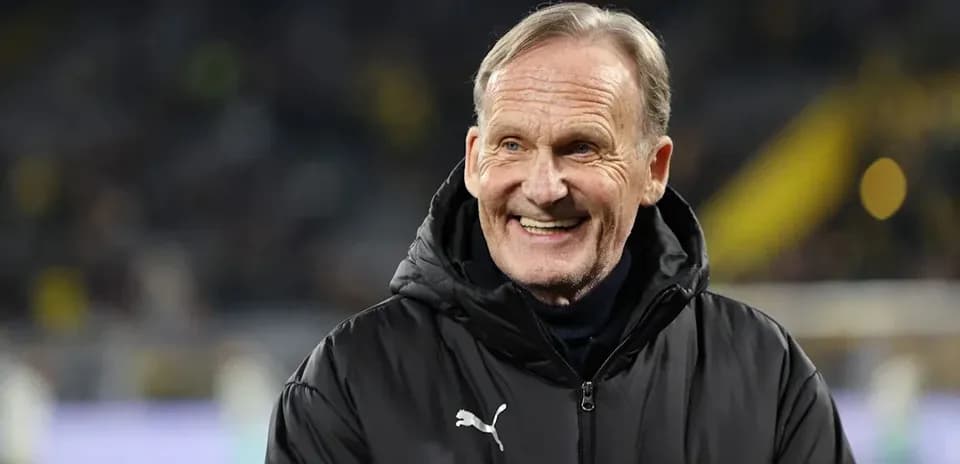 Man in black coat smiling at football match