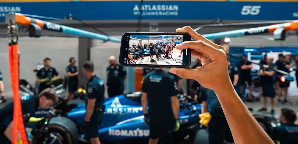 Person photographing Williams Racing team in garage