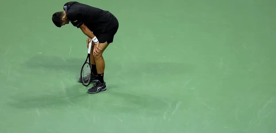 Tennis player bent over on green court