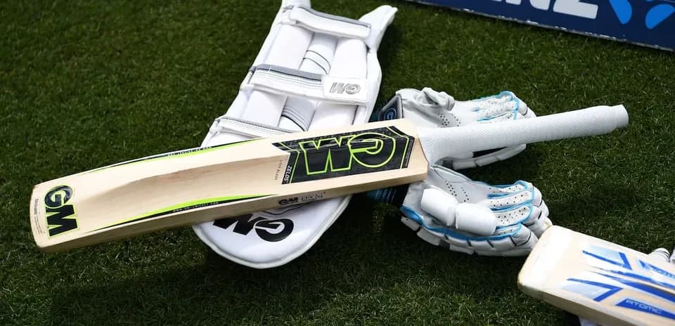 Cricket bat, gloves, and pads on the grass
