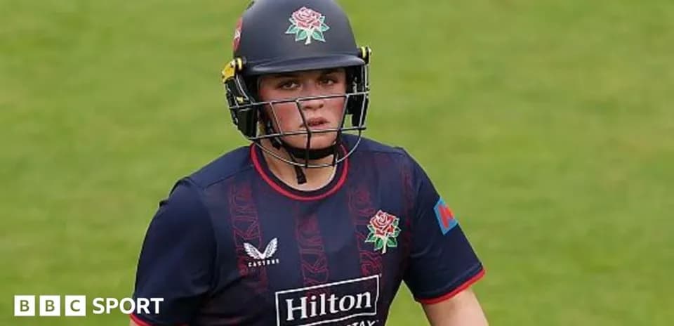 Cricketer wearing helmet and team uniform on field