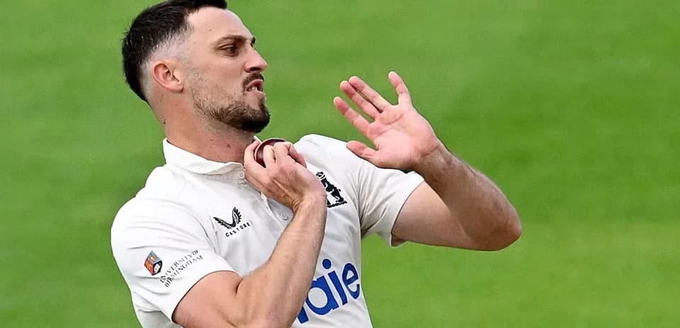 Cricketer adjusting his collar during match play
