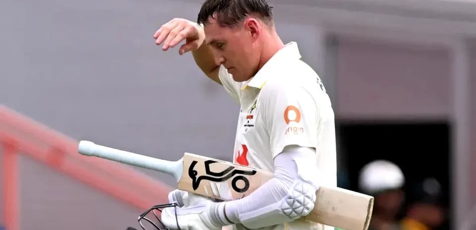 Cricketer walking off the field with bat in hand
