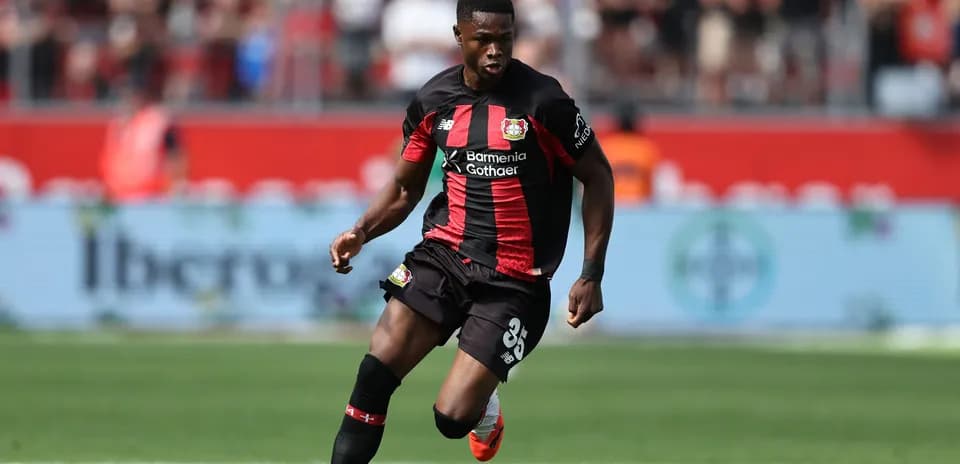 Player in black and red kit dribbling ball on pitch