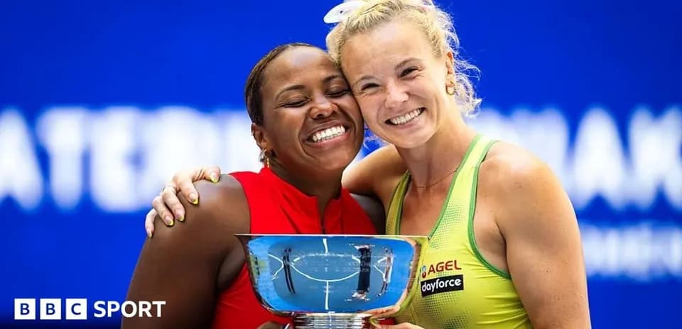 Two tennis players celebrating with trophy after match
