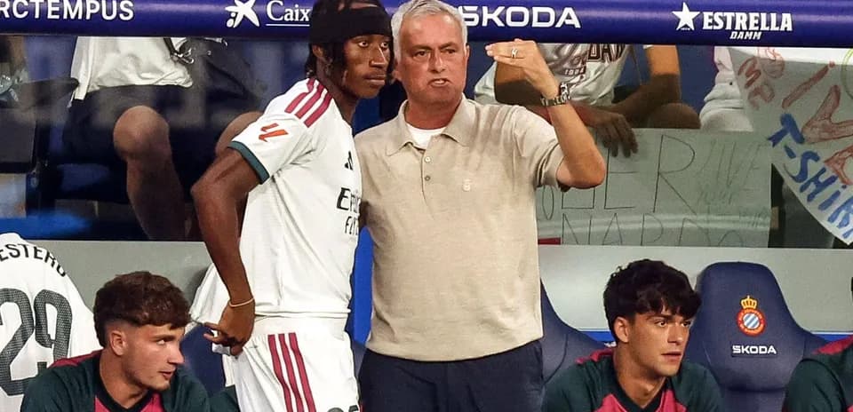 Coach speaking to player on bench during match