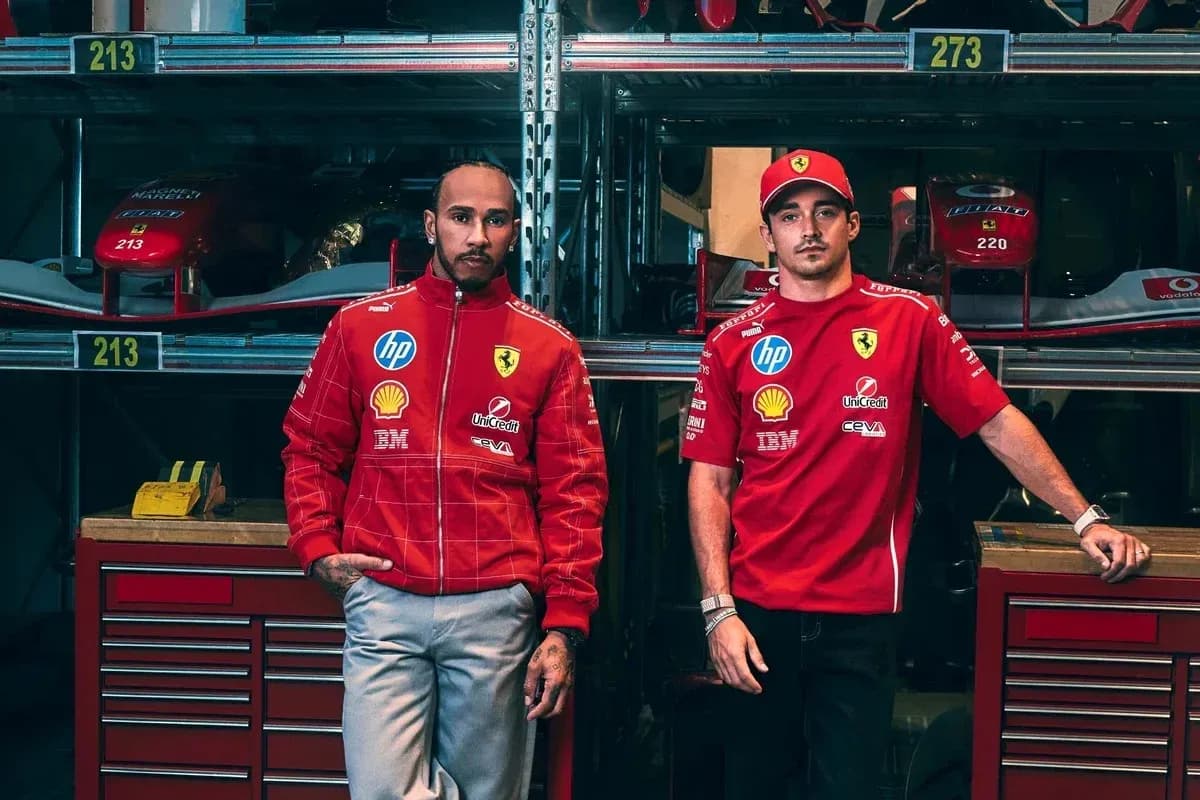 Two drivers in Ferrari team gear beside cars Two drivers in Ferrari team gear beside cars