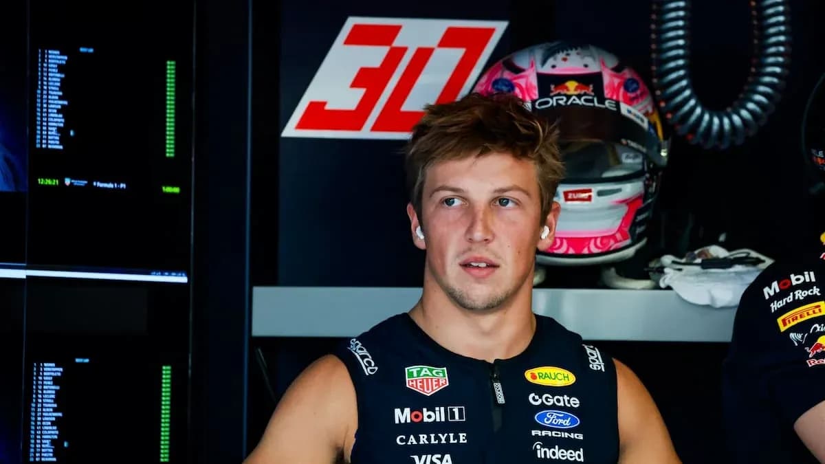 Driver in team garage with racing helmet behind Driver in team garage with racing helmet behind