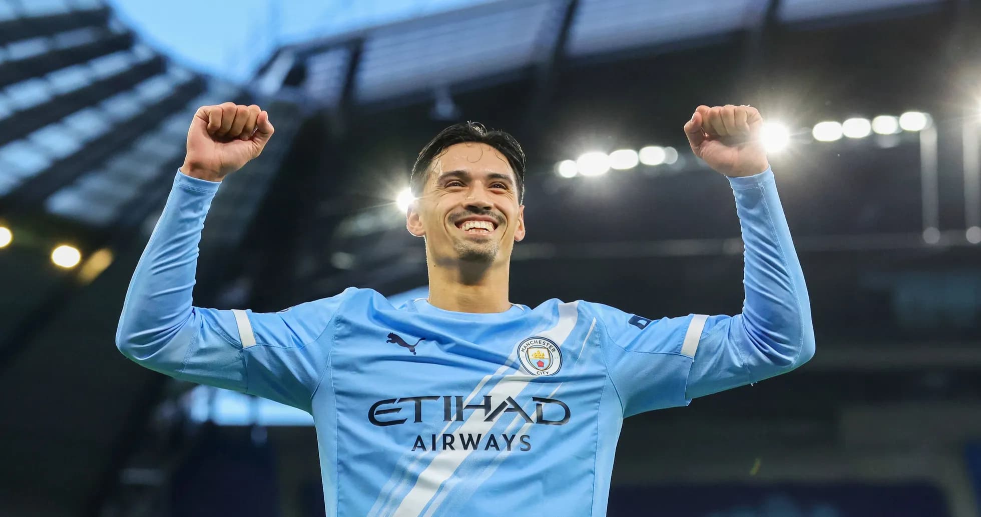 Player celebrating with raised arms in Manchester City jersey Player celebrating with raised arms in Manchester City jersey