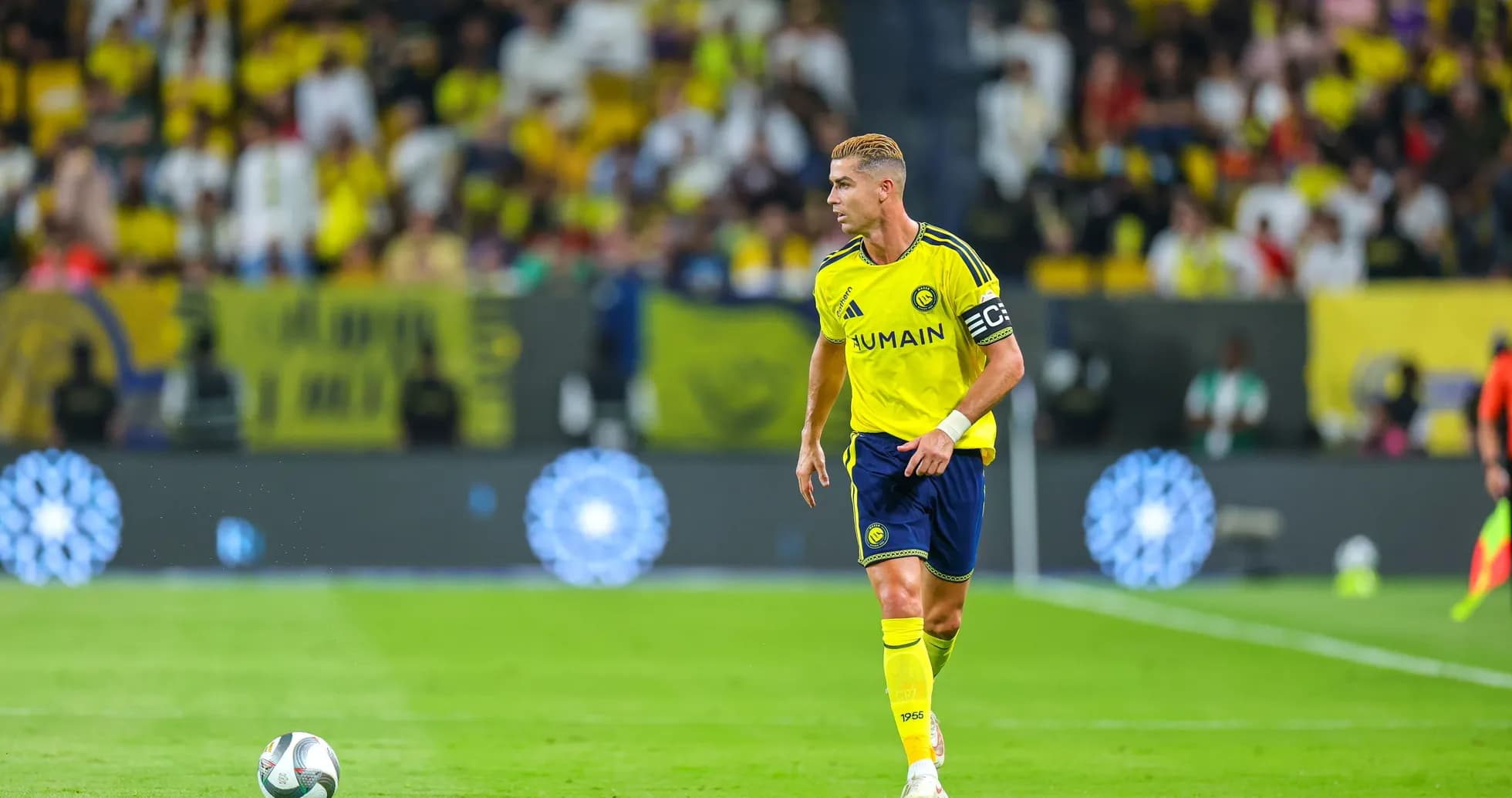 Player in yellow jersey with captain's armband on field Player in yellow jersey with captain's armband on field