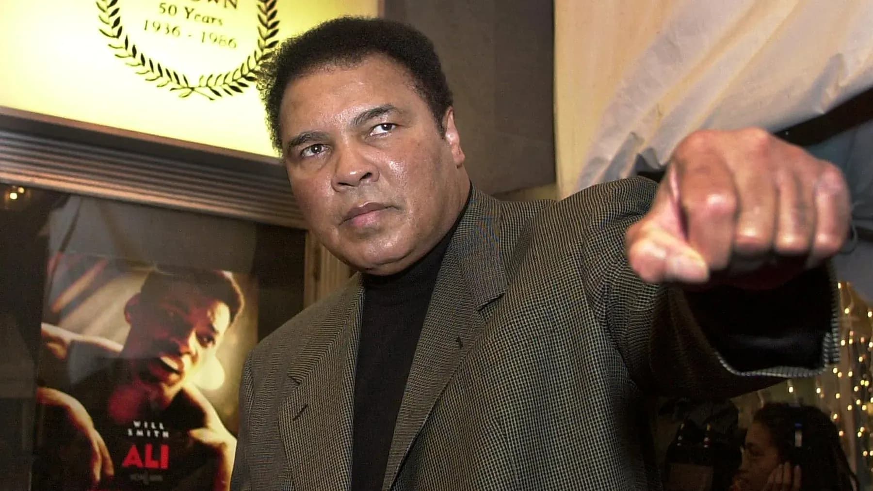Man raising fist at event with movie poster behind Man raising fist at event with movie poster behind