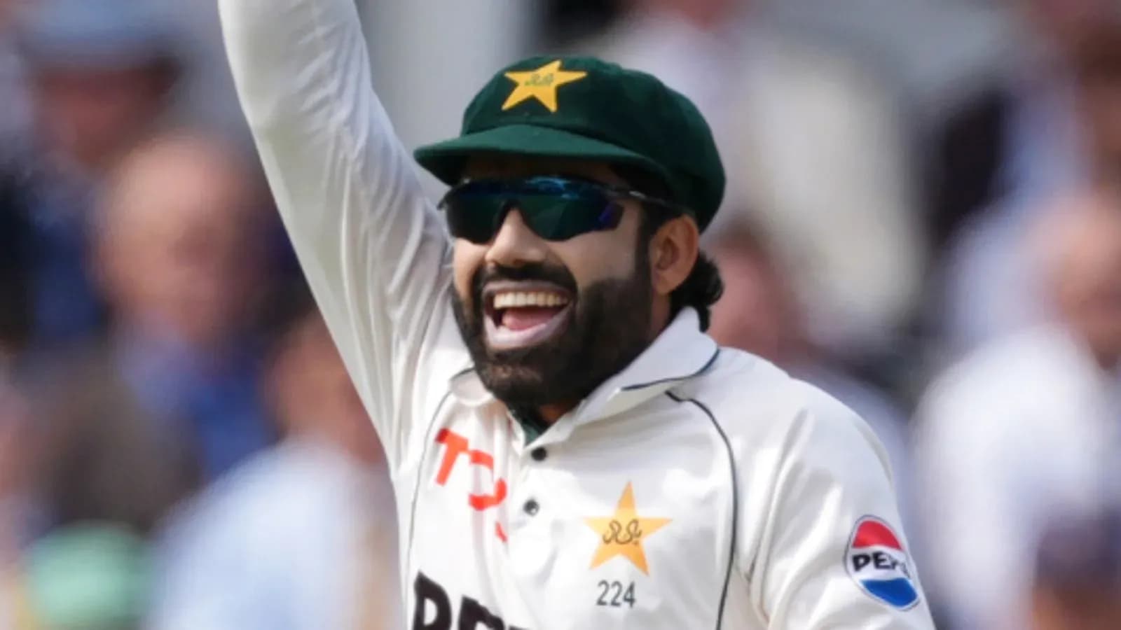 Cricketer celebrating with raised arm on field Cricketer celebrating with raised arm on field