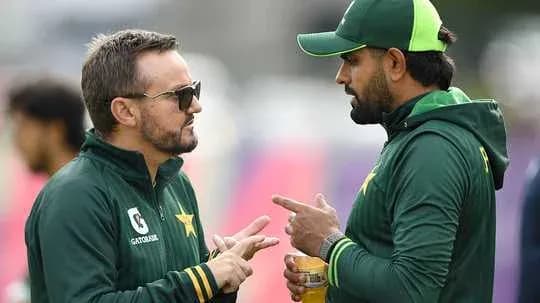 Two cricket team members discussing strategies on field Two cricket team members discussing strategies on field