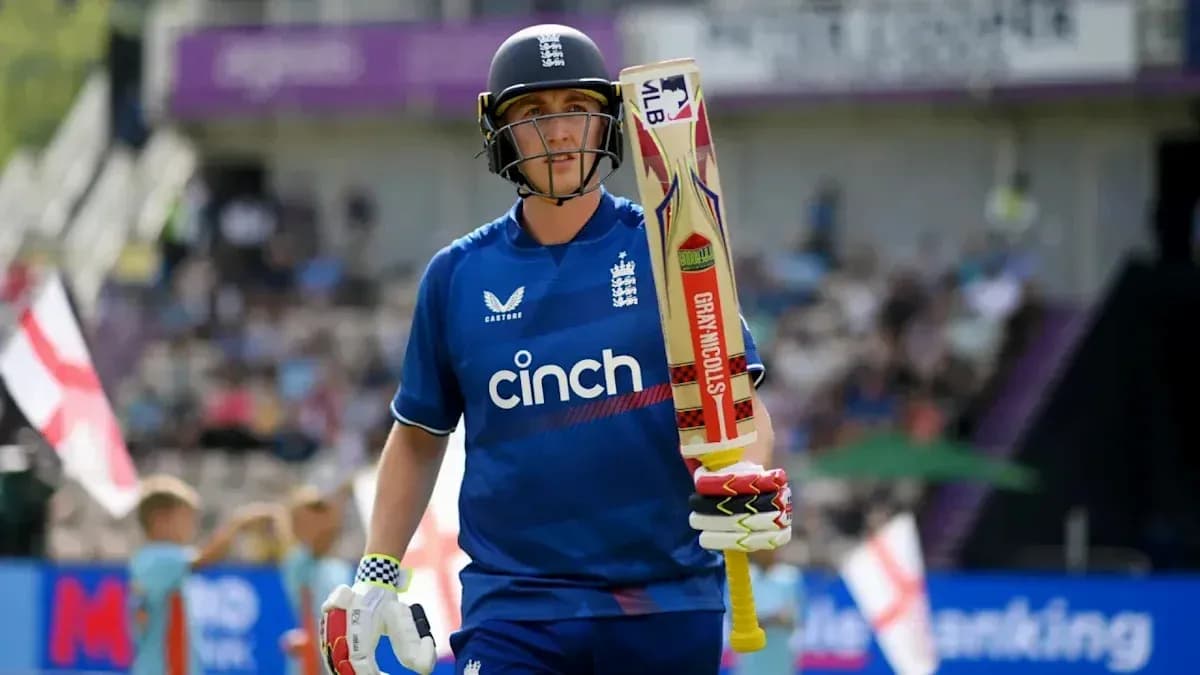 Cricketer in blue kit walking with bat Cricketer in blue kit walking with bat