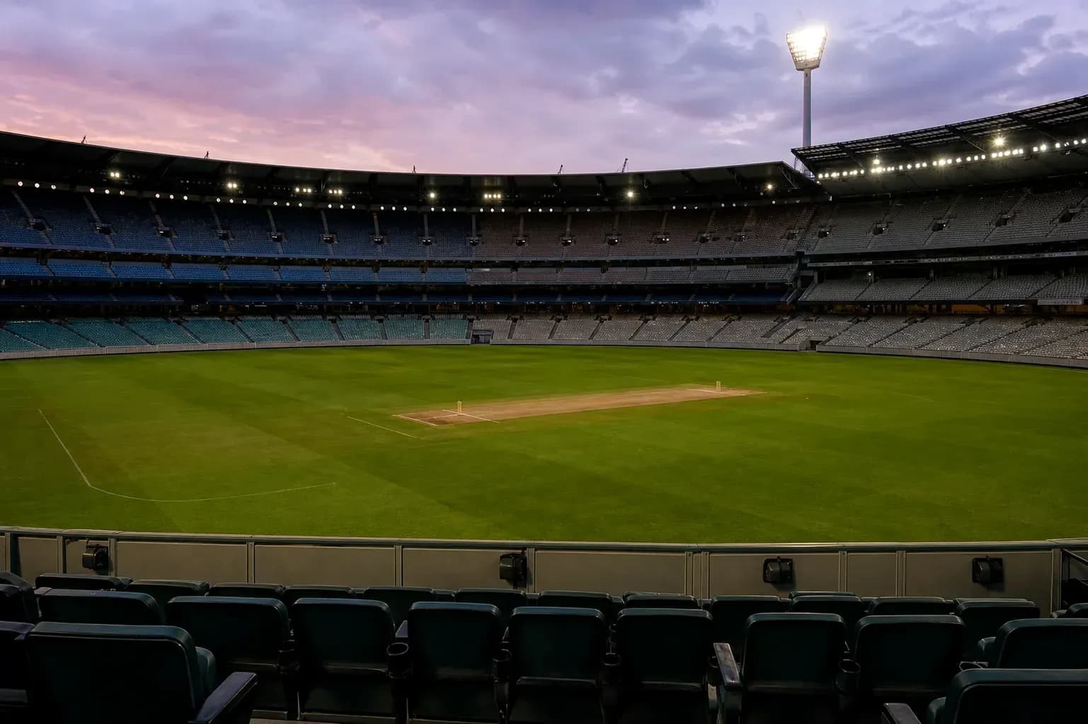 Empty cricket stadium with pitch at dusk Empty cricket stadium with pitch at dusk