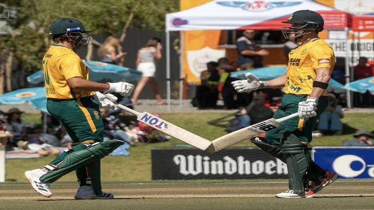 Two cricket players celebrating with bats on field Two cricket players celebrating with bats on field