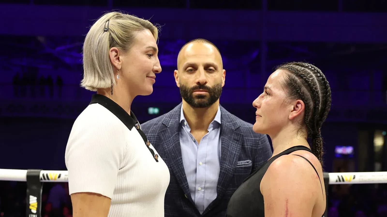 Two fighters facing off with a referee present Two fighters facing off with a referee present