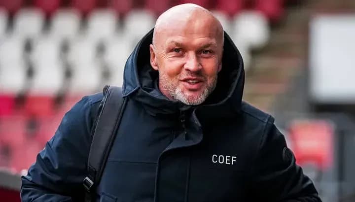 Man in a coat smiling while entering stadium Man in a coat smiling while entering stadium
