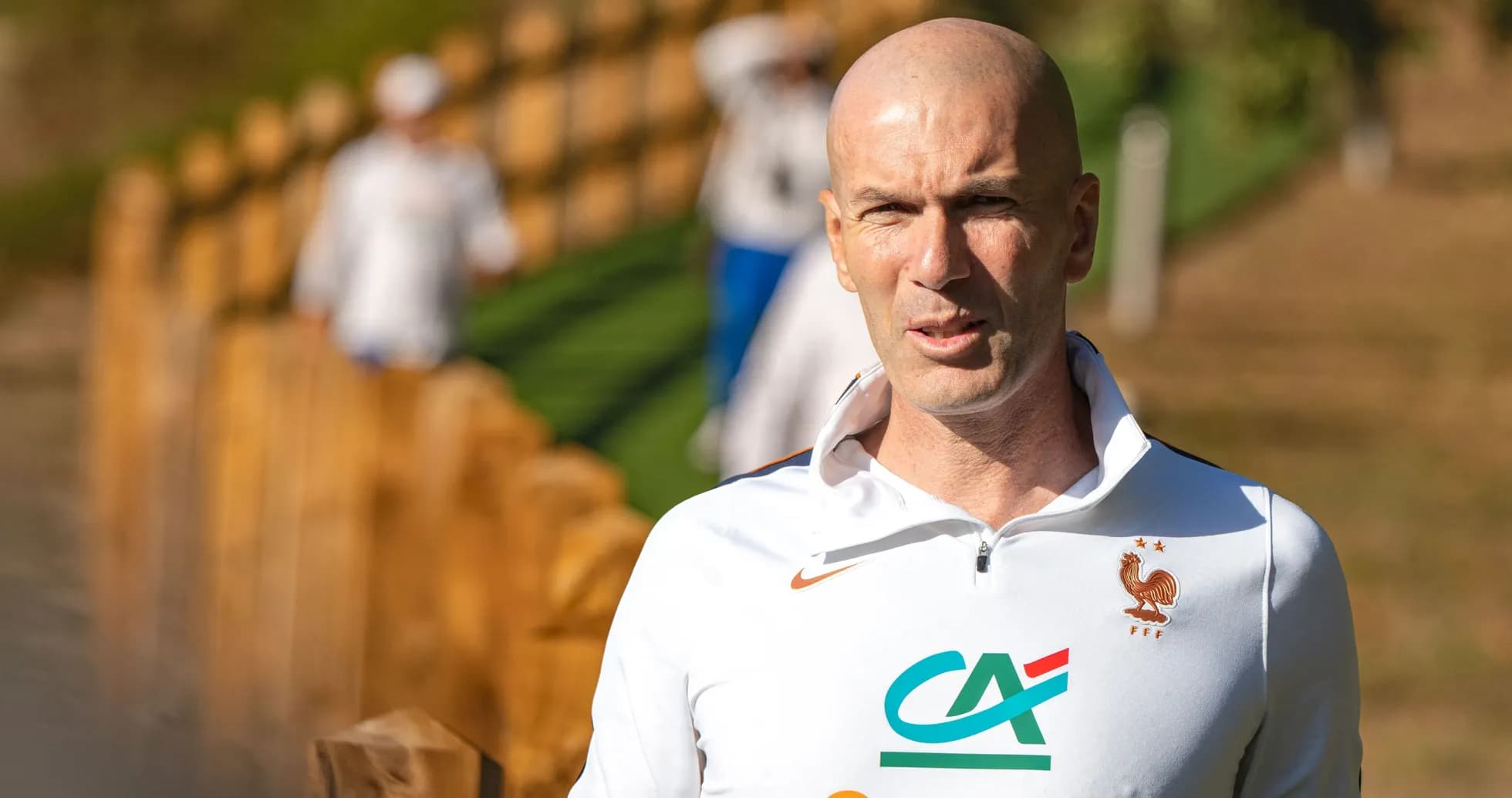 Coach walking near training ground with players behind Coach walking near training ground with players behind