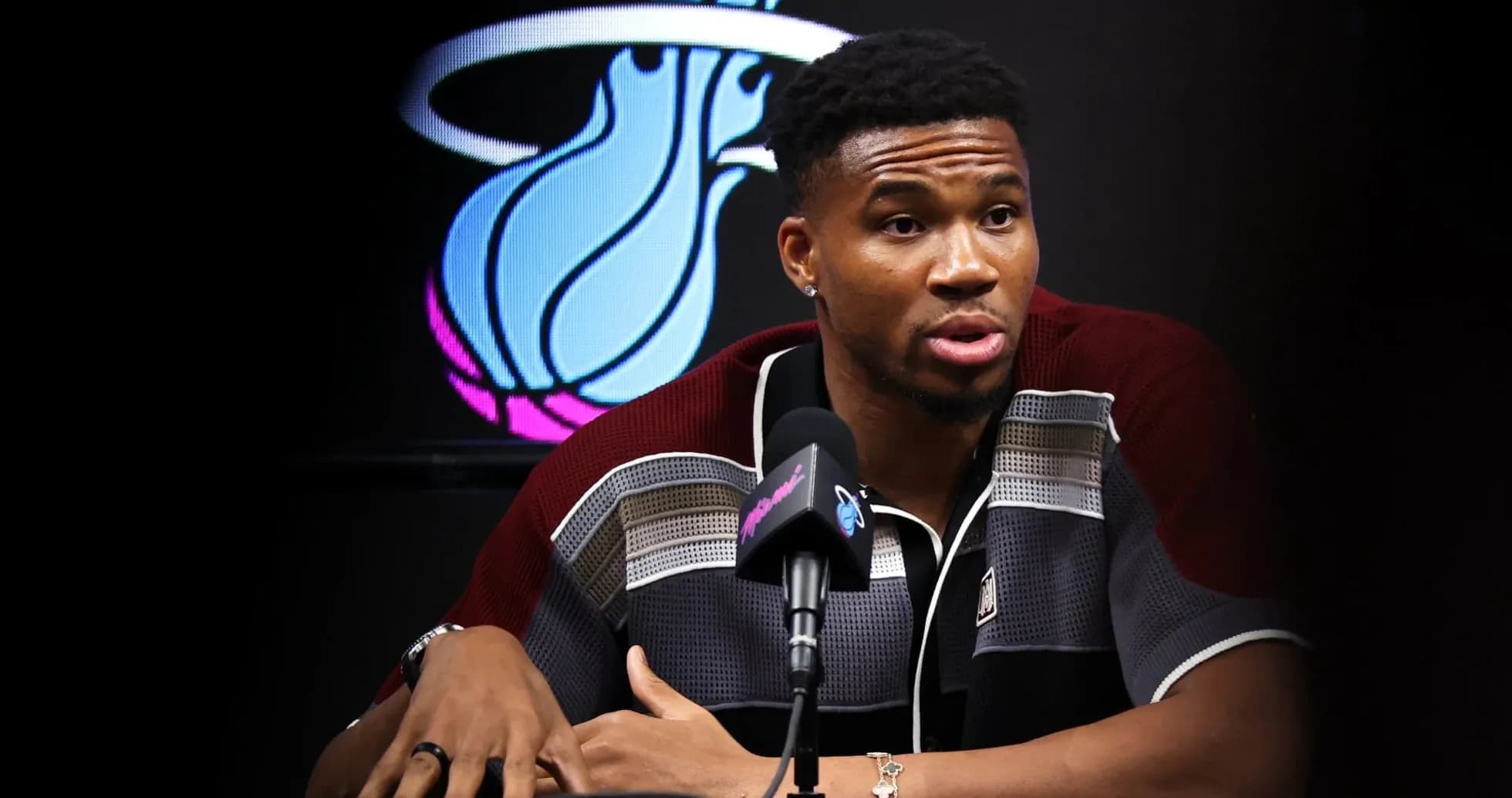 Player speaking at press conference with team logo behind Player speaking at press conference with team logo behind
