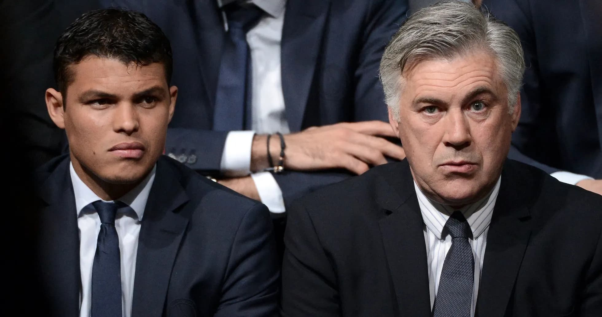 Two men in suits seated during an event Two men in suits seated during an event