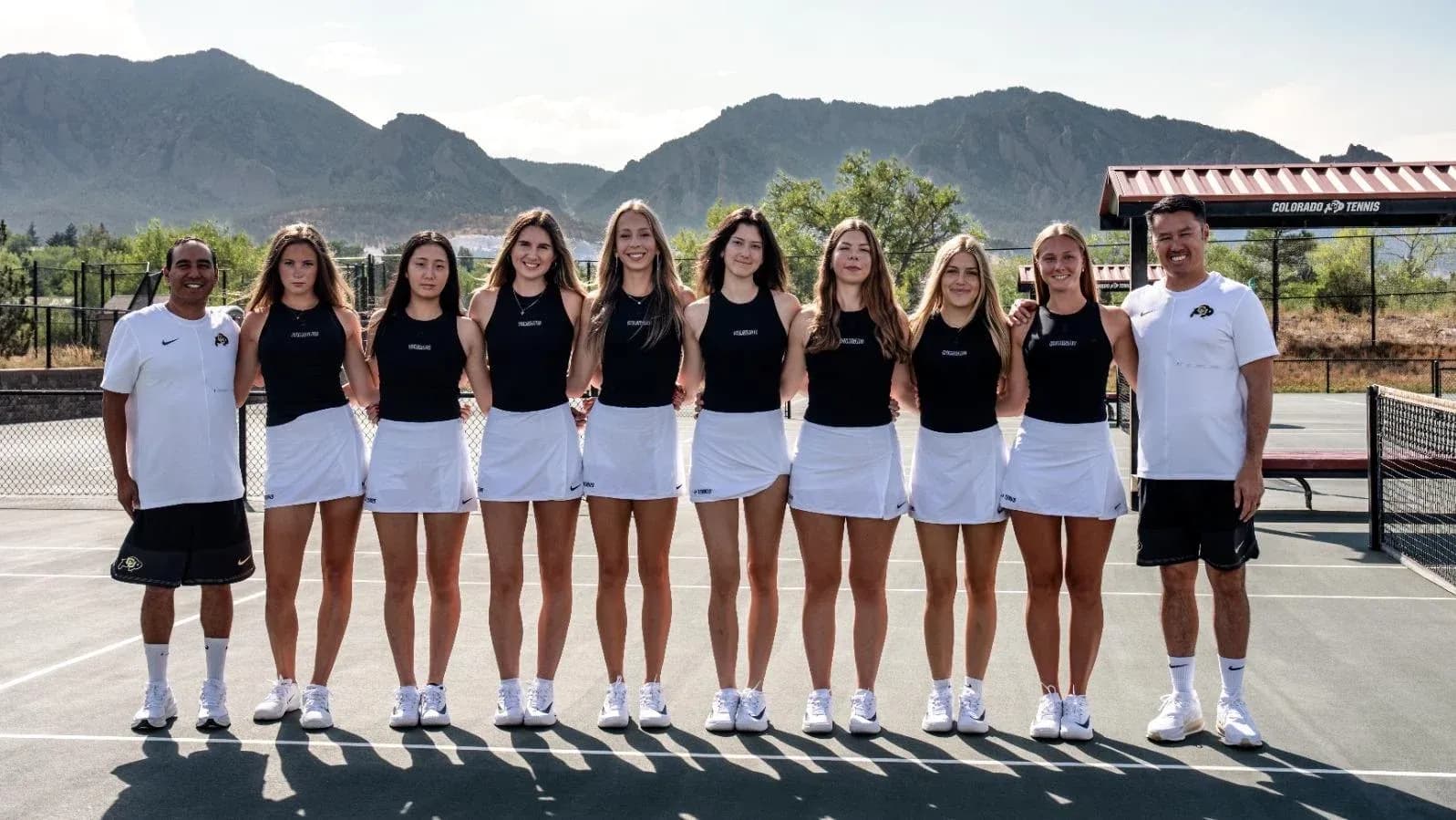 Tennis team posing together on court with coaches Tennis team posing together on court with coaches