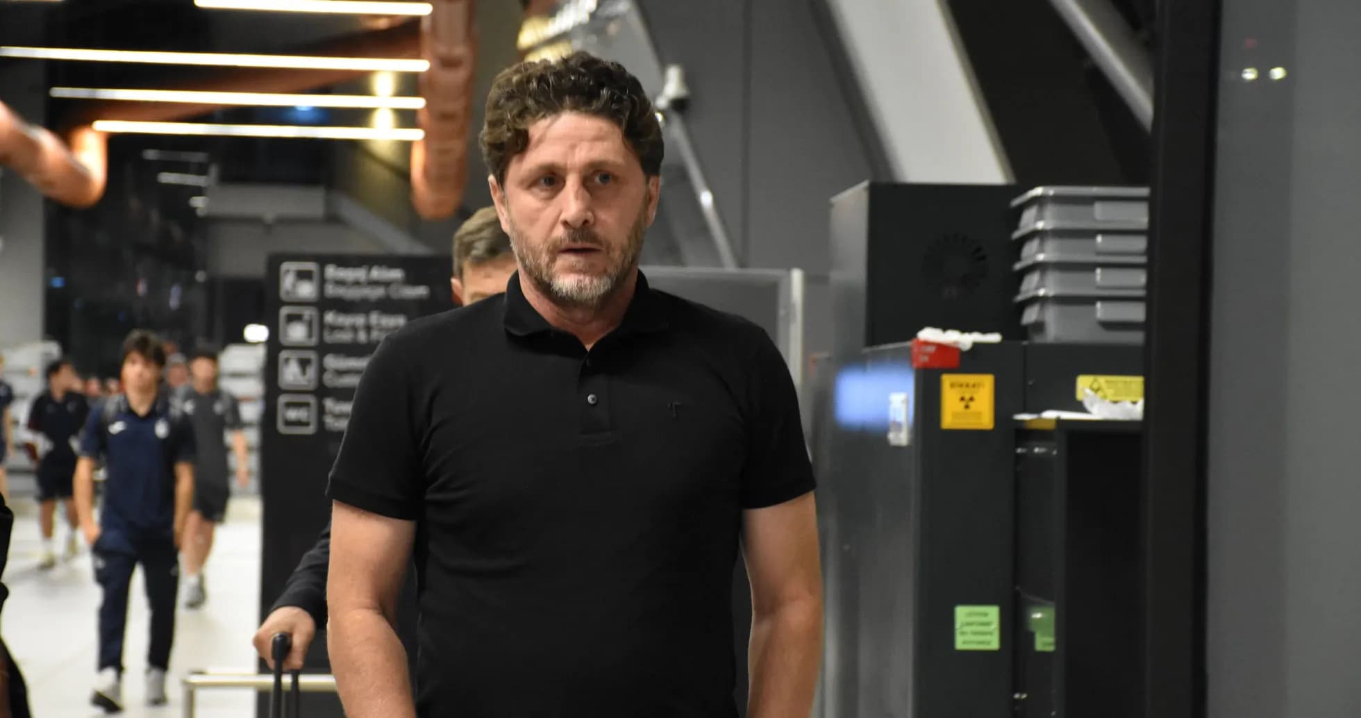 Man in black polo walking through airport terminal Man in black polo walking through airport terminal
