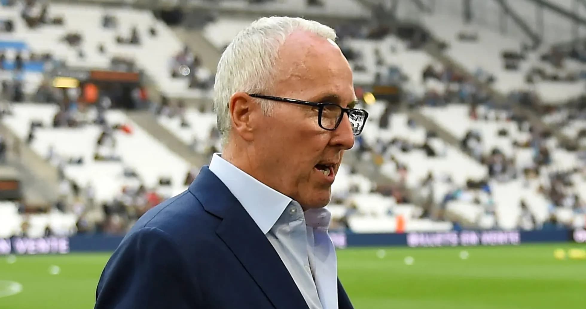 Man in suit speaking on the sidelines of a stadium Man in suit speaking on the sidelines of a stadium