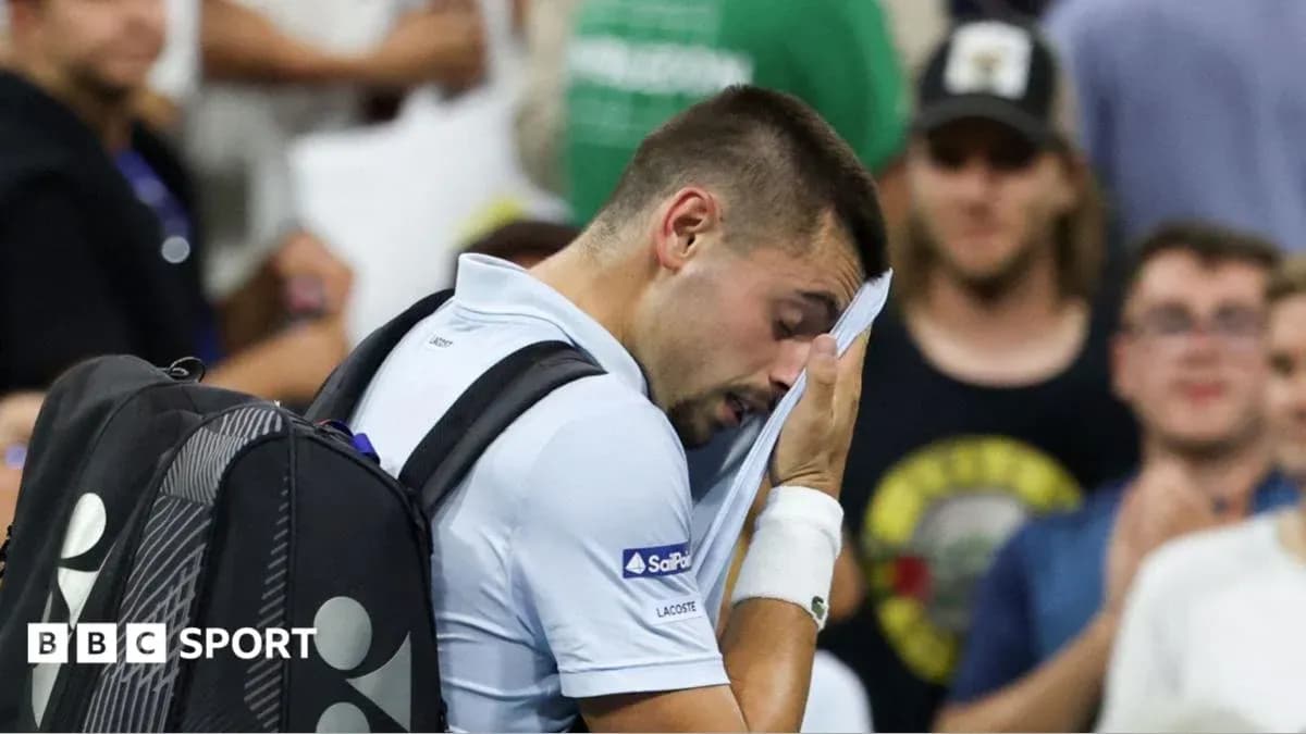 Tennis player wiping face with towel during match Tennis player wiping face with towel during match