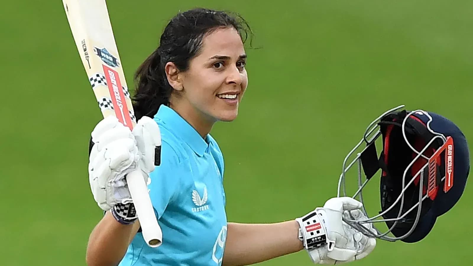 Cricketer celebrating with bat and helmet raised Cricketer celebrating with bat and helmet raised