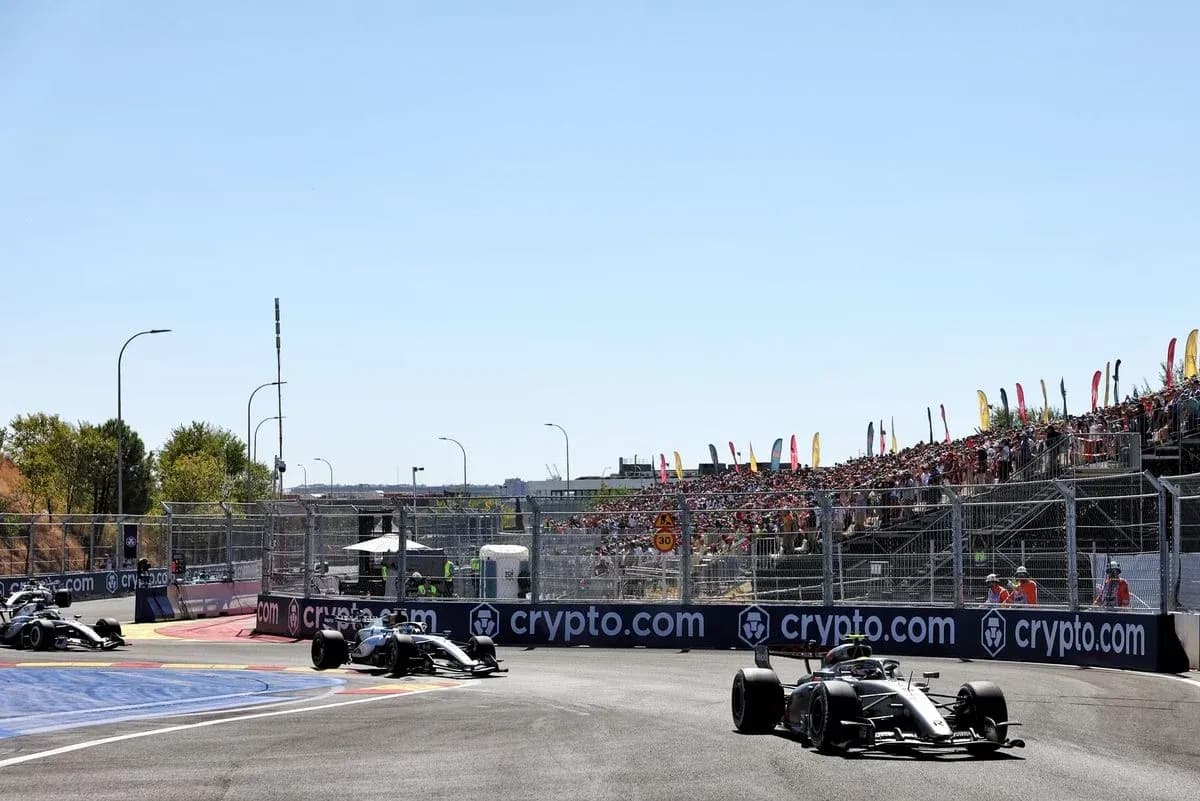 Two Formula 1 cars racing on track with crowd Two Formula 1 cars racing on track with crowd
