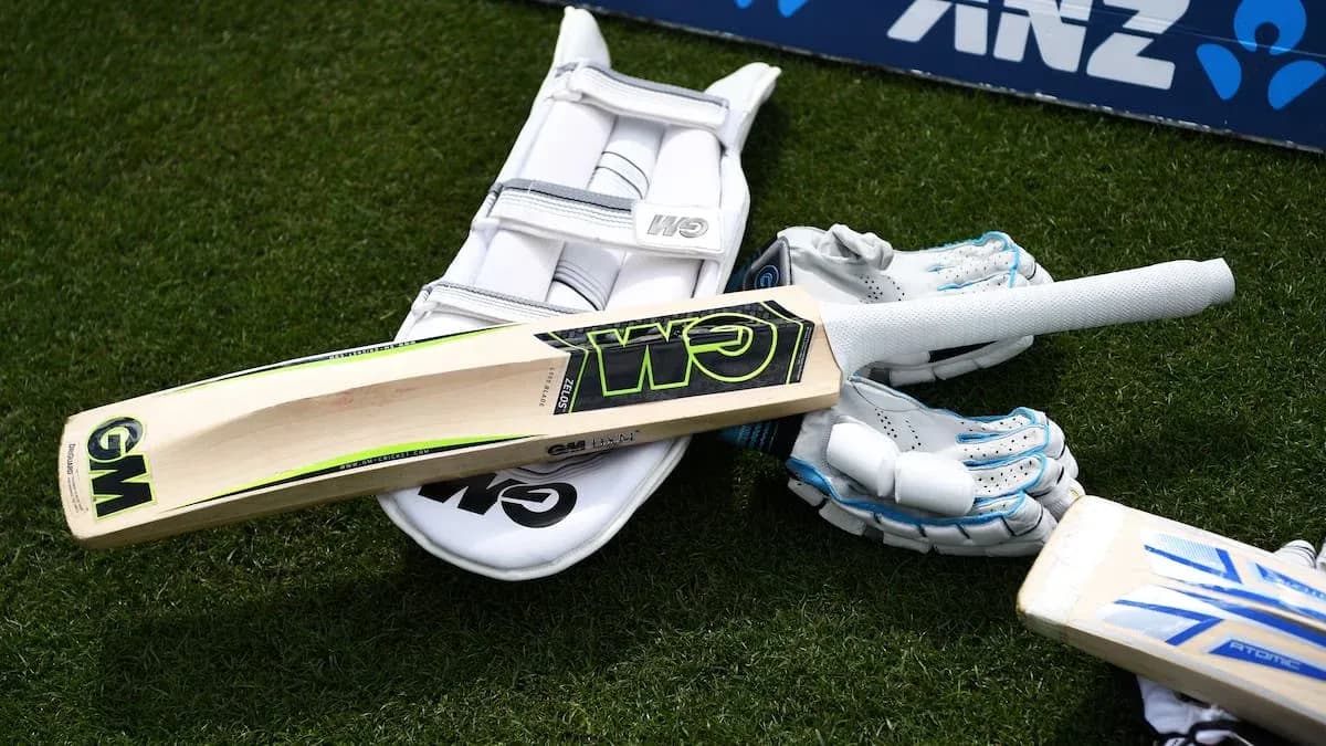 Cricket bat, gloves, and pads on the grass Cricket bat, gloves, and pads on the grass